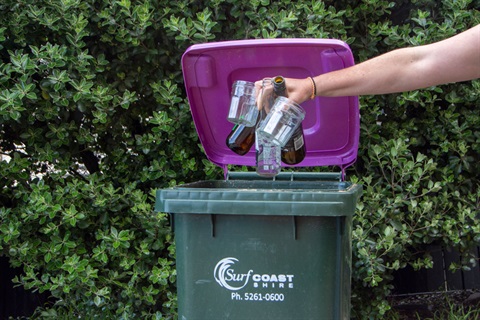 hand putting glass into the purple-lidded bin