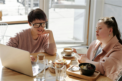 Two people working together on a laptop at a table